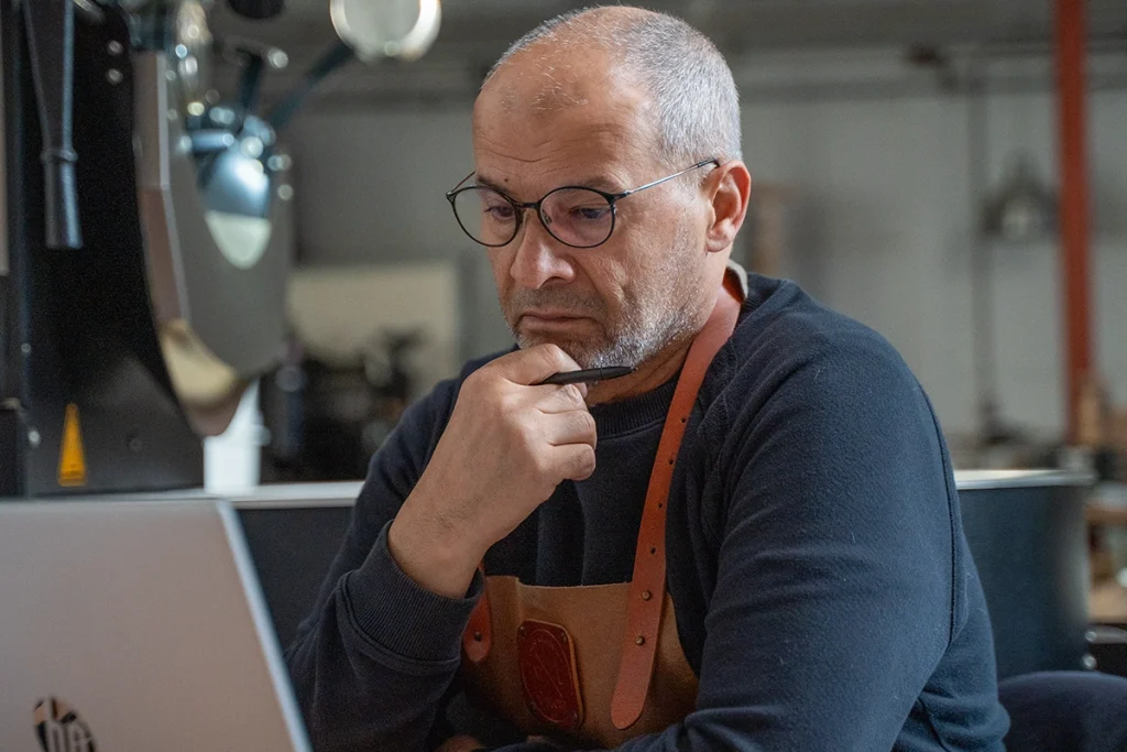 Koffiebrander van Lorando & Morini die in de branderij het brandproces van koffie analyseert achter een laptop.