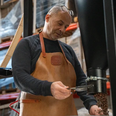 Dos van Lorando & Morini controleert vers gebrande koffiebonen die uit de koffiebrander komen.